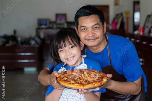 Happy asian father and daughter preparing homemade pizza