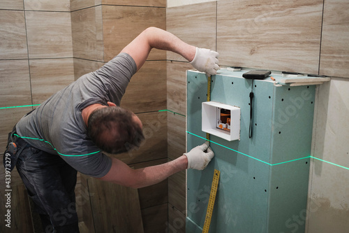tiler arranges wall tiles in the bathroom