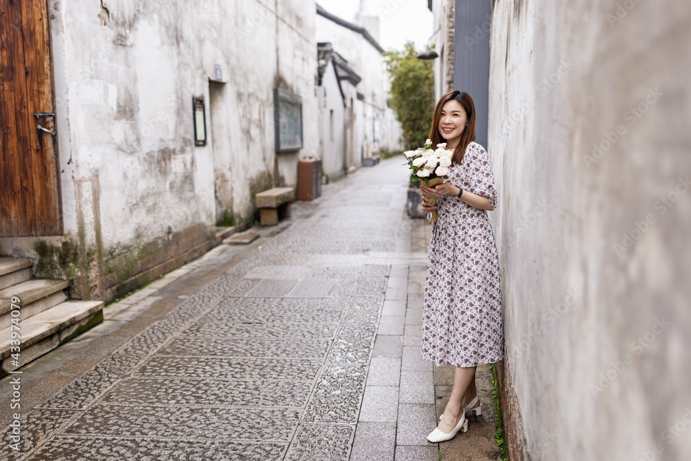 Portrait of young asian woman wearing stylish summer dress and walking outdoor in old city. Happy stylish woman with smiley face enjoys life