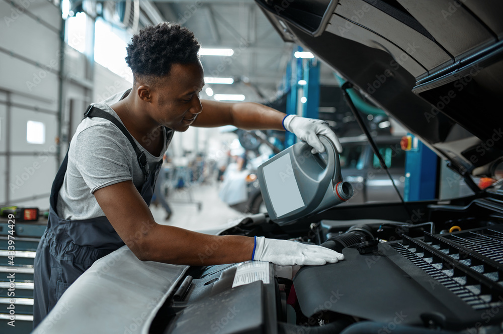 Male worker changes oil in engine, car service Male worker changes oil in engine, car service