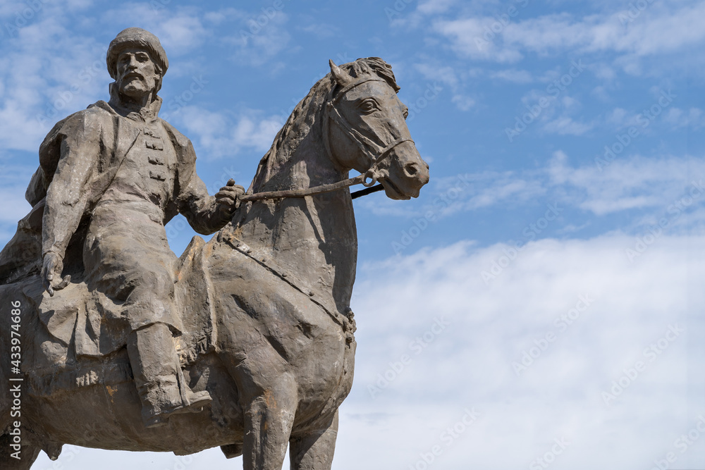 Obraz premium Medieval Russian prince on horseback. Close-up stone sculpture against the backdrop of a beautiful blue sky with clouds.