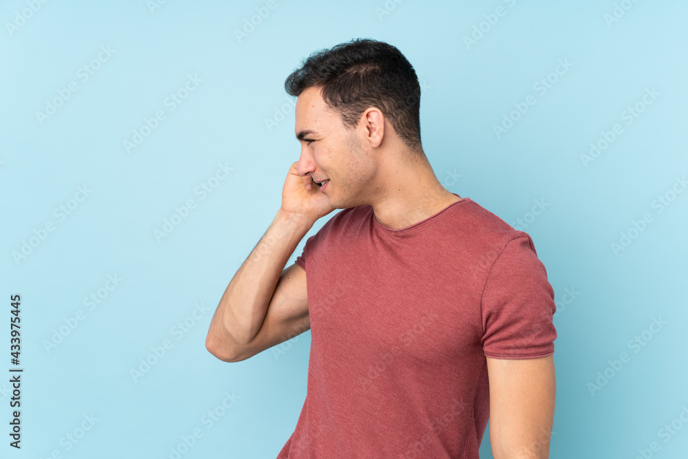 Young caucasian handsome man isolated on blue background keeping a conversation with the mobile phone with someone Young caucasian handsome man isolated on blue background keeping a conversation with the mobile phone with someone