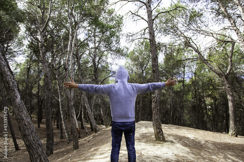 Man in forest with arms in cross