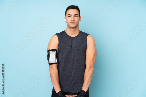 Young sport man over isolated on blue background stretching arm © luismolinero