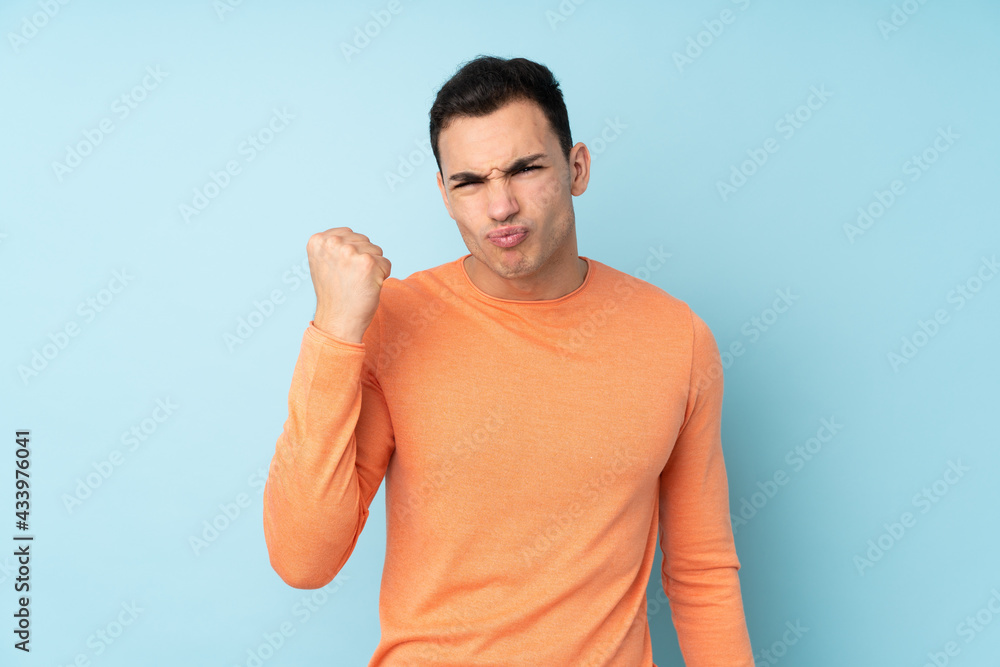 Young caucasian handsome man isolated on blue background with angry gesture Young caucasian handsome man isolated on blue background with angry gesture