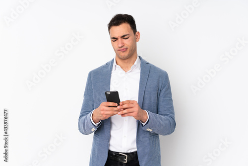 Young handsome businessman on isolated background thinking and sending a message © luismolinero
