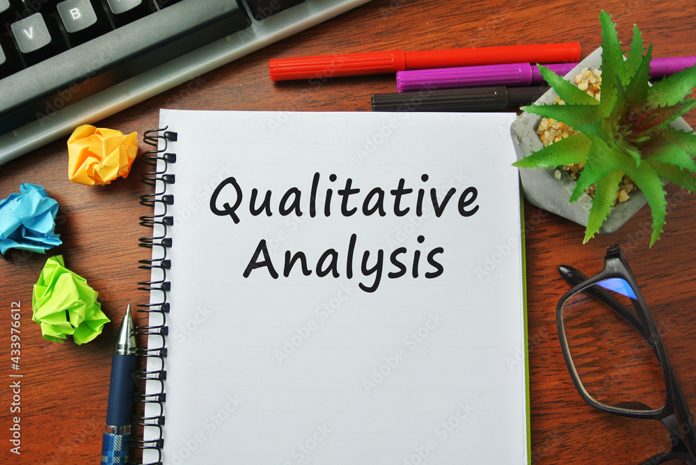 Selective focus of marker pen, scramble of paper, spectacle, and notebook written with QUALITATIVE ANALYSIS. Selective focus of marker pen, scramble of paper, spectacle, and notebook written with QUALITATIVE ANALYSIS.