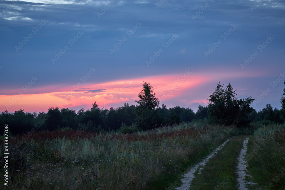 Dramatic sky on summer sunset with road. Beautiful clouds.