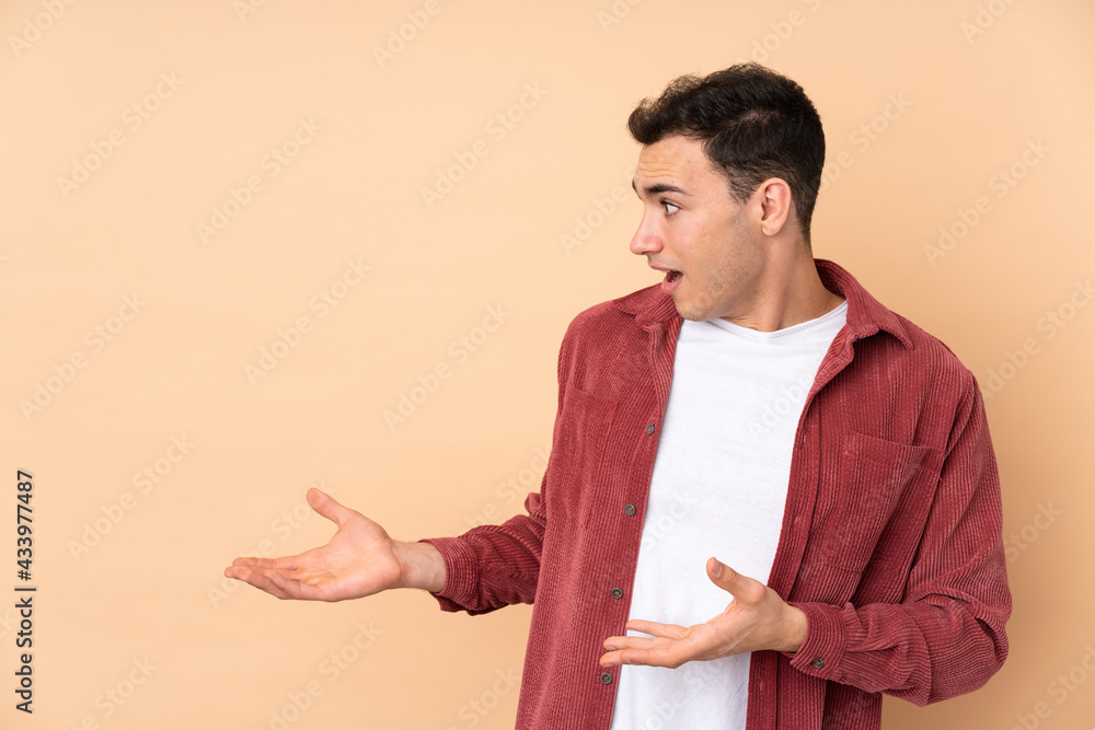 Young caucasian handsome man isolated on beige background with surprise facial expression Young caucasian handsome man isolated on beige background with surprise facial expression