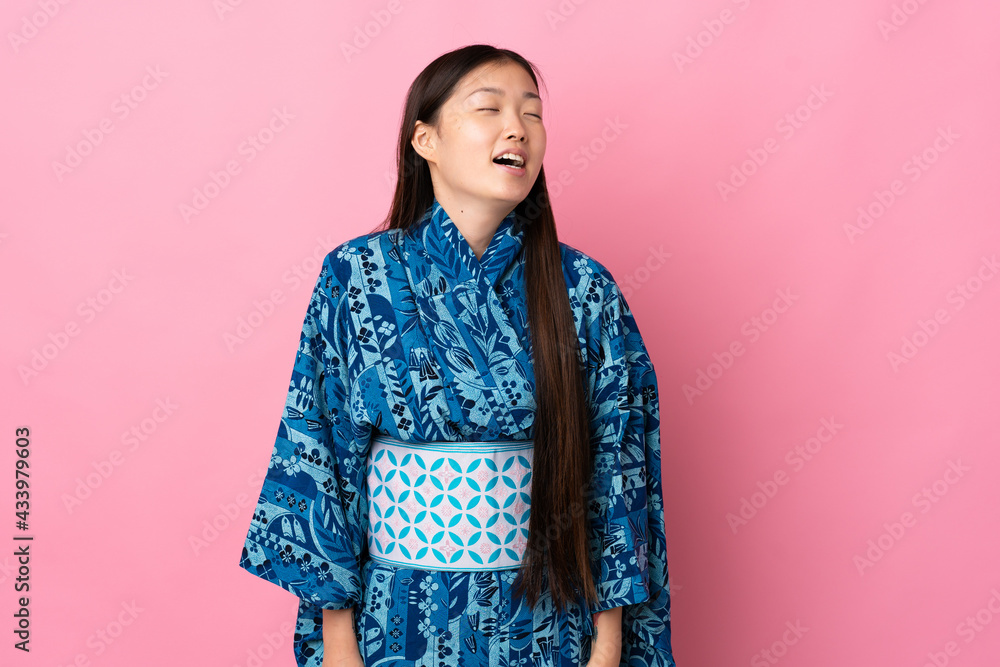 Young Chinese girl wearing kimono over isolated background laughing