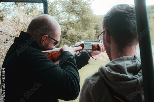 Two men practicing clay shooting. One teaching the other newbie the ropes. Cold winter day in the UK