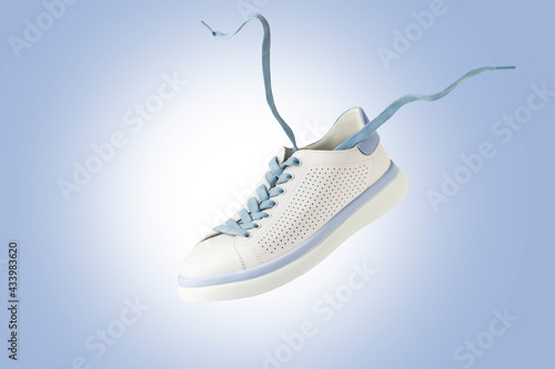 White sneakers flying. Fashionable sports shoes with laces.