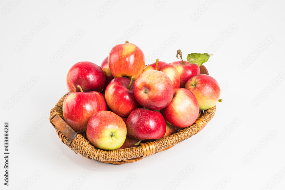 Bright multi-colored fresh apples in a wicker basket on a white background. Selective focus. Bright multi-colored fresh apples in a wicker basket on a white background. Selective focus.