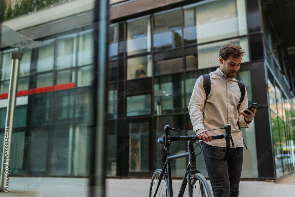 Businessman commuting to work with his bicycle and using phone Businessman commuting to work with his bicycle and using phone