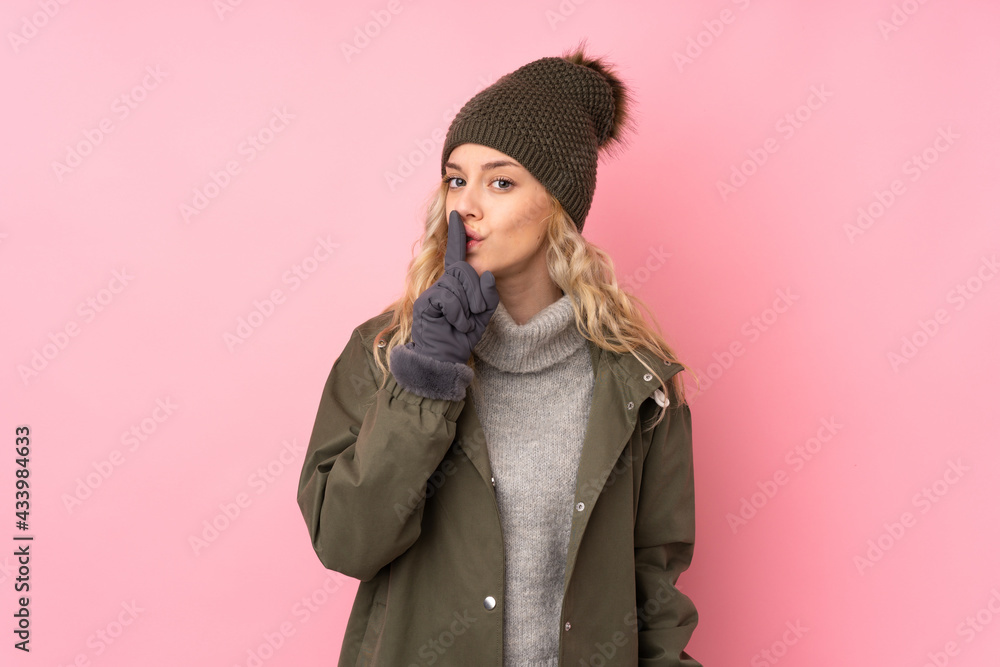 Young girl with winter hat isolated on pink background doing silence gesture Young girl with winter hat isolated on pink background doing silence gesture