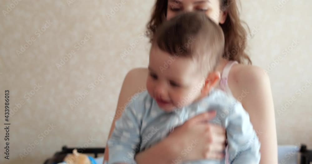 mom holds the baby in her arms and plays with him. Little cute Son plays with mom at home mom holds the baby in her arms and plays with him. Little cute Son plays with mom at home