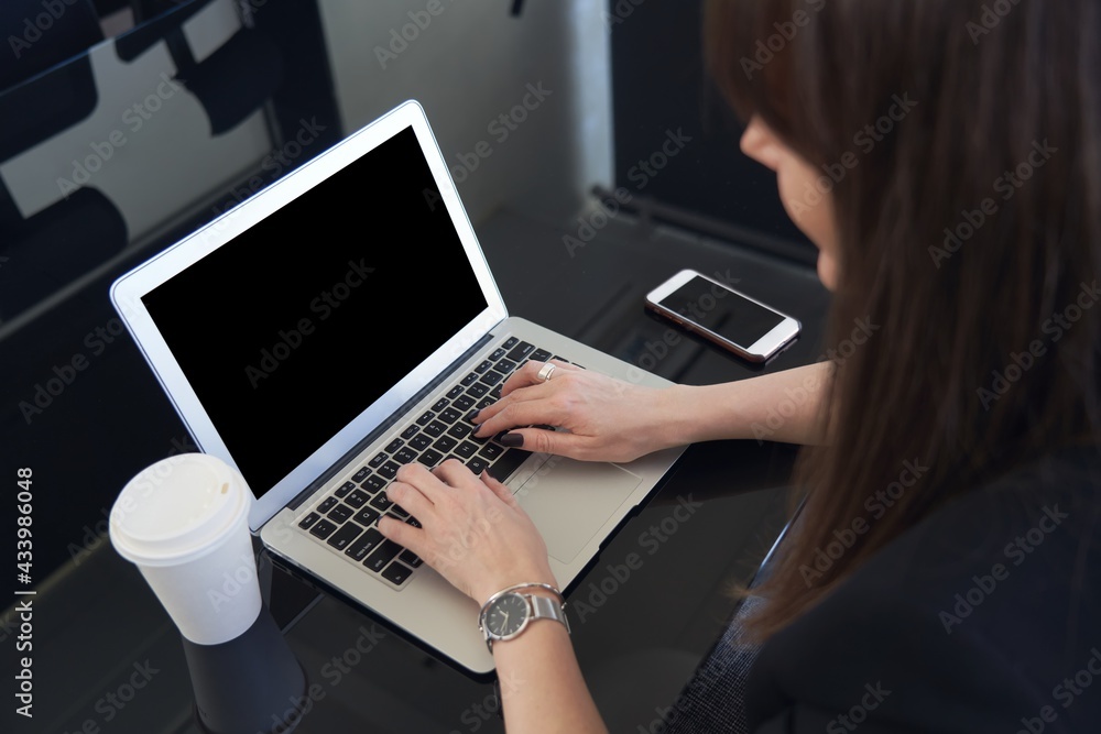 Woman working on laptop computer in the office. Focus on empty blank screen monitor. Woman working on laptop computer in the office. Focus on empty blank screen monitor.