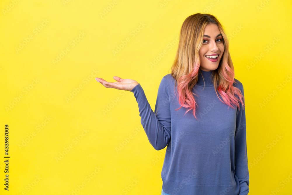 Young woman over isolated yellow background holding copyspace imaginary on the palm to insert an ad Young woman over isolated yellow background holding copyspace imaginary on the palm to insert an ad