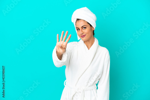 Young woman in a bathrobe over isolated blue background happy and counting four with fingers