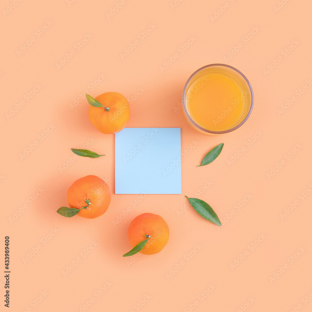 Flat lay composition with fresh tangerines, glass with juice and empty stick note on orange background.