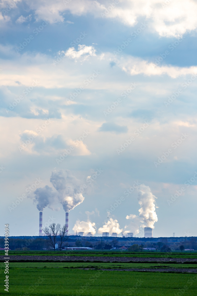 A view of the smoking chimneys of a distant coal-fired power plant on the horizon. Photo taken in natural daylight, late afternoon.