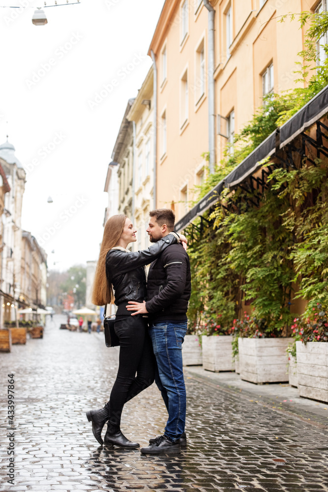 Young couple guy and girl in black jackets walking through the streets of the city, happy couple, romantic date