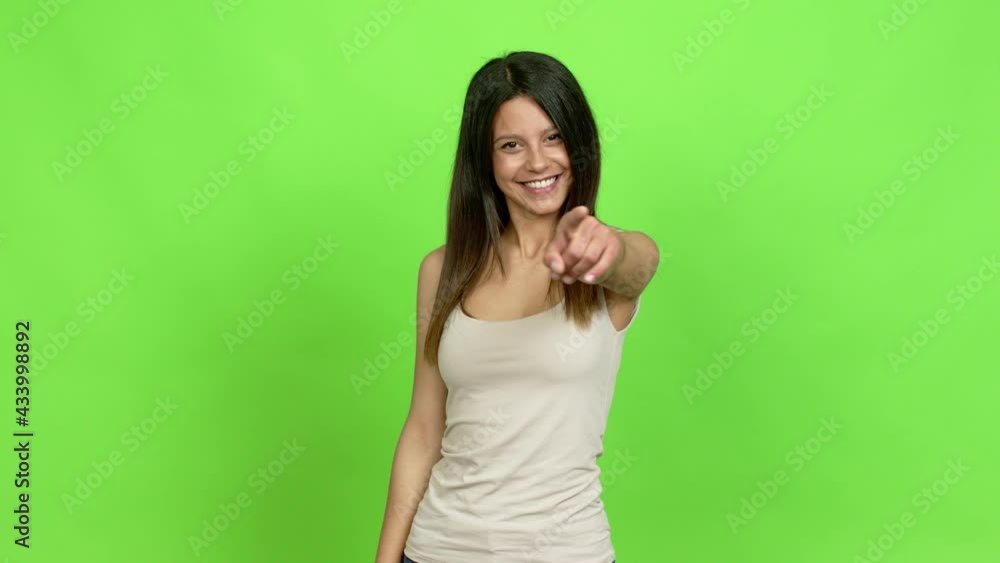 Young woman points finger at you with a confident expression over isolated background Young woman points finger at you with a confident expression over isolated background