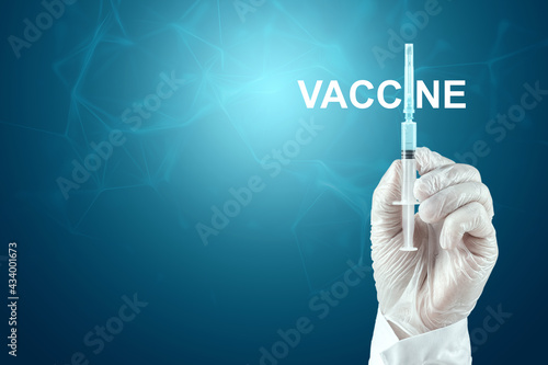 A doctor's gloved hand holds a syringe containing the COVID-19 vaccine. Medical research, close-up.