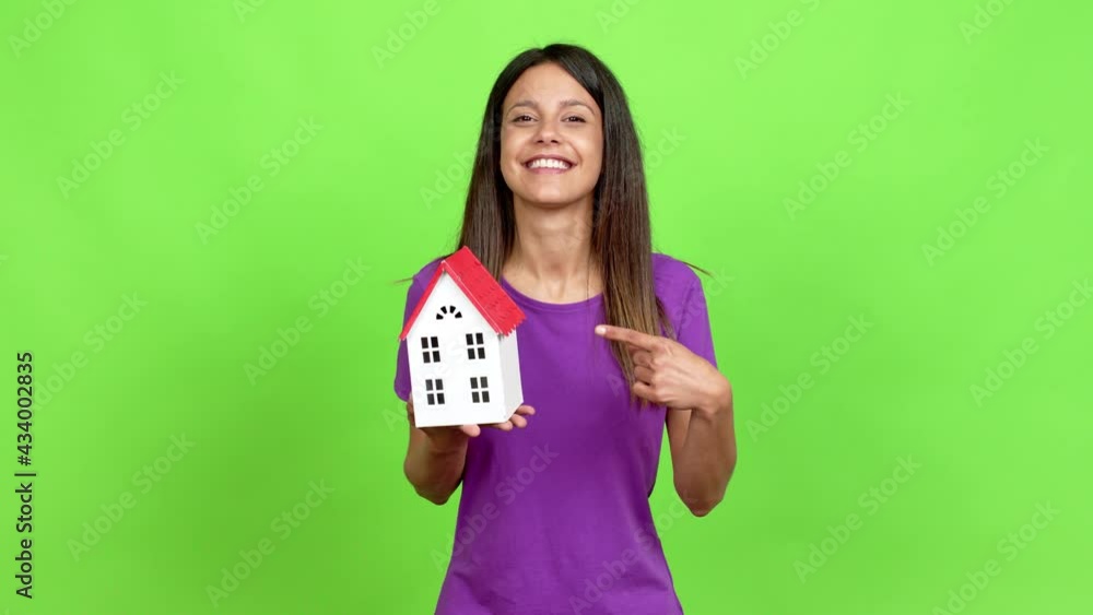 Young woman holding a little house over isolated background Young woman holding a little house over isolated background