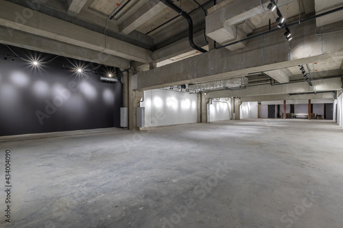 Fotografia empty interior of large concrete room as warehouse or hangar with spotlights