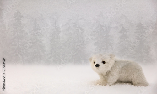A cute little white polar bear walking in the snow with a forest of trees in the blurred background.