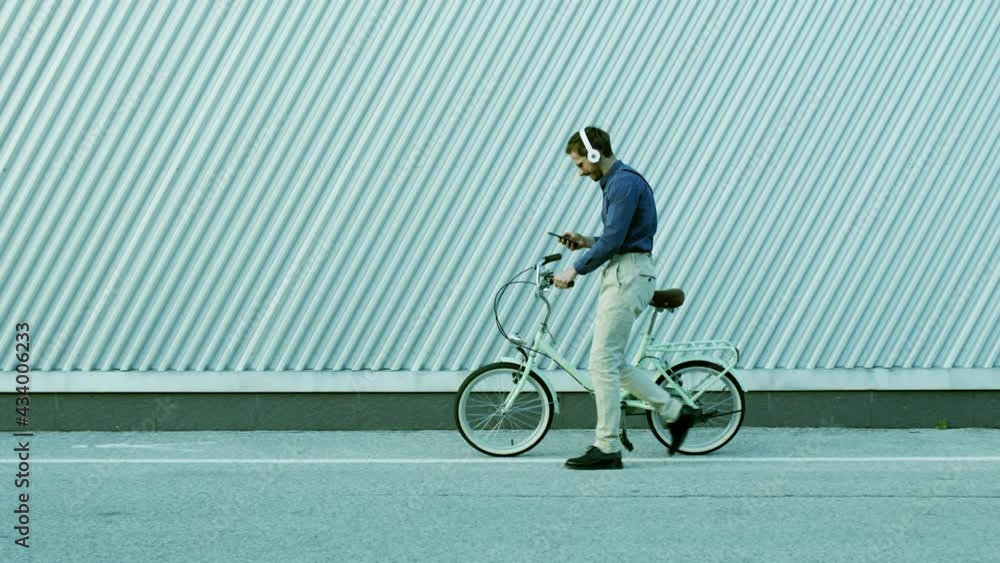 Young man walks with bicycle background urban environment. Generation z, stylish man, braces. Young man walks with bicycle background urban environment. Generation z, stylish man, braces.