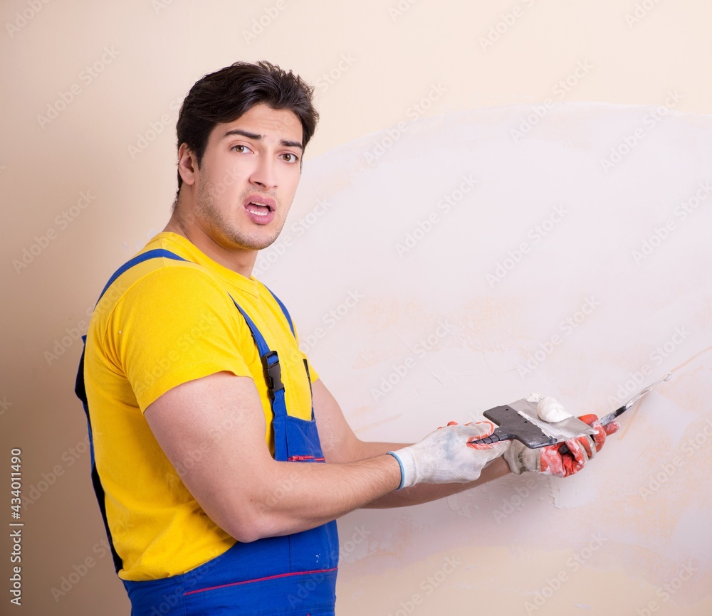 Young contractor employee applying plaster on wall Young contractor employee applying plaster on wall