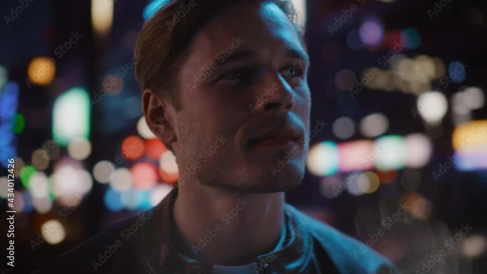 Handsome Blonde Man Walking Through Night City. Thoughtful Attractive Young Man Traveling, Looking Around Urban Center Contemplating Business Ideas, Future Career. Medium Closeup Tracking Shot Handsome Blonde Man Walking Through Night City. Thoughtful Attractive Young Man Traveling, Looking Around Urban Center Contemplating Business Ideas, Future Career. Medium Closeup Tracking Shot