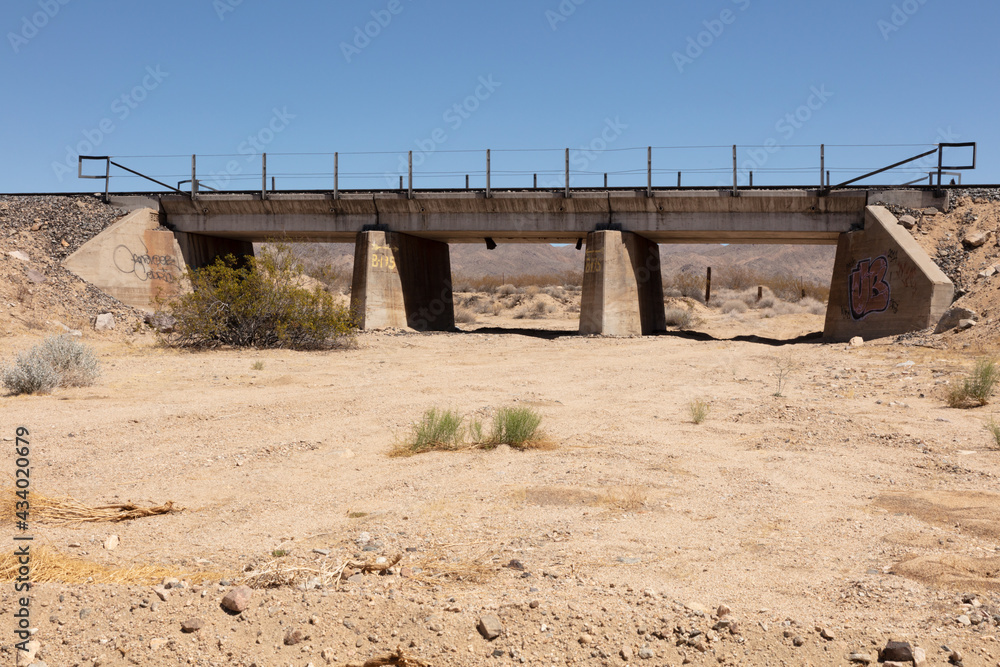 dry wadi in the middle of the Mojave desert under a blue sky dry wadi in the middle of the Mojave desert under a blue sky