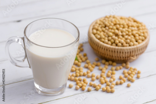 Soy and soy milk in a glass with soybeans in wooden bowl background