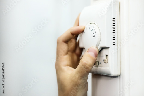 Human hand on the air conditioner temperature controller. Service for the installation and configuration of climate equipment.