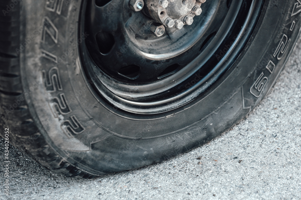 Flat car wheel close-up. A problem on the way. A punctured wheel on the road. Flat car wheel close-up. A problem on the way. A punctured wheel on the road.