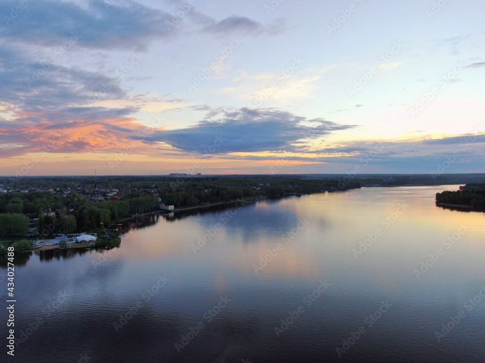 Aerial view sunset on the river. Colorful clouds are reflected in the water. Beautiful panorama of nature at sunset.