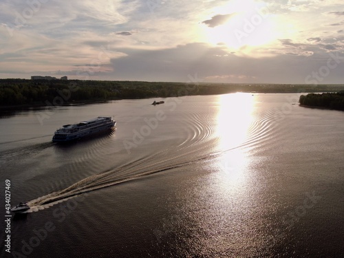 Aerial view passenger cruise ship sails along the river at sunset. Beautiful panorama of nature at sunset. Cruise trip.