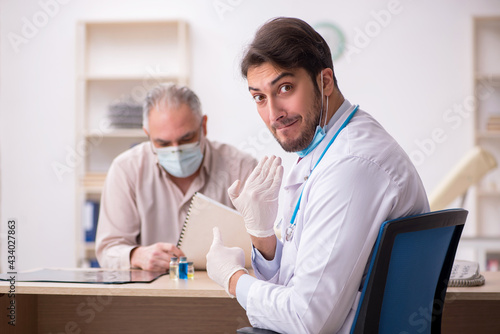 Old male patient visiting young male doctor in vaccination conce © Elnur