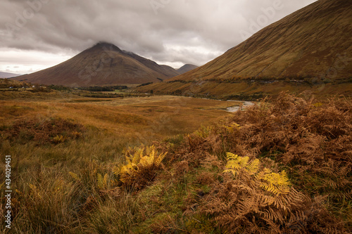 Autumn landscape in Highlands, Scotland, United Kingdom. Beautiful mountains with rainy clouds in background.