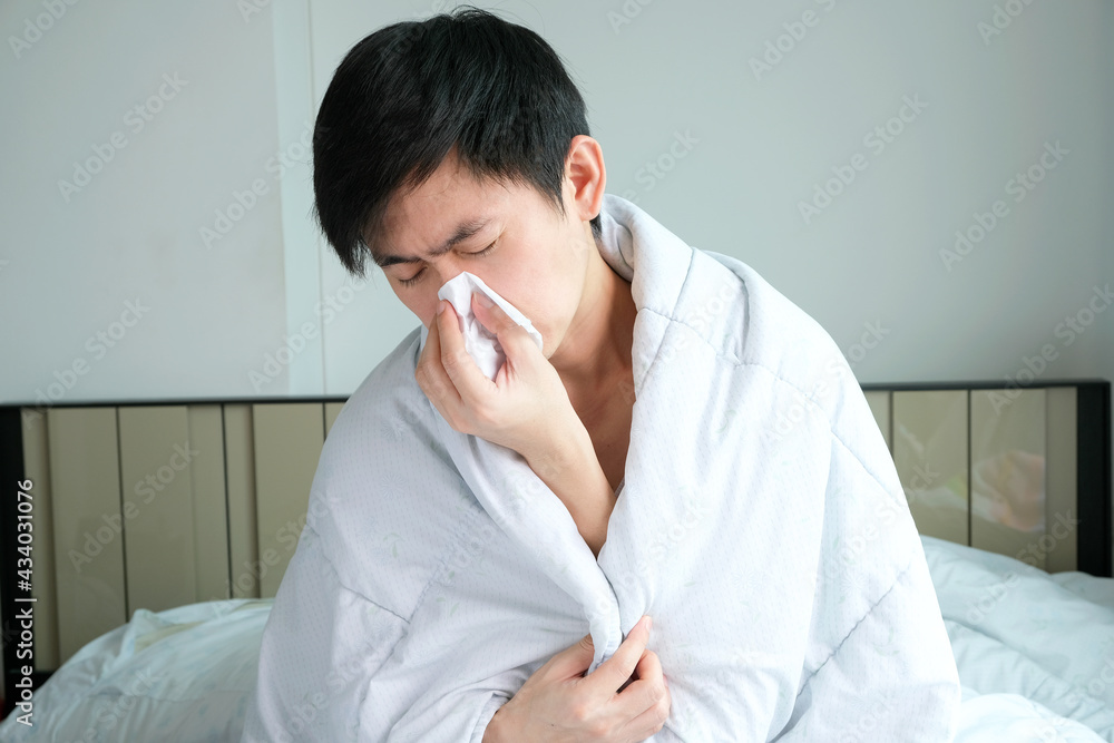 Sick man is flu, using a paper napkin and he have a runny nose. And he was covered in warm cloth.Health concept Sick man is flu, using a paper napkin and he have a runny nose. And he was covered in warm cloth.Health concept
