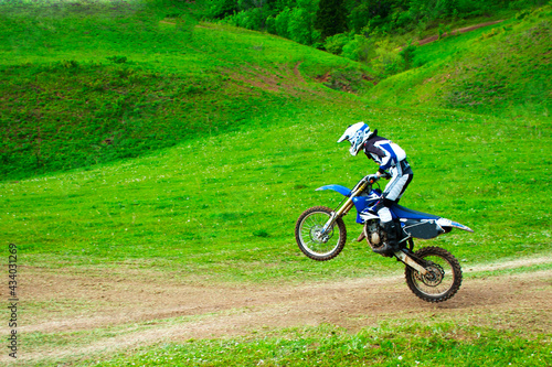 a professional motorcyclist rides off-road on one rear wheel