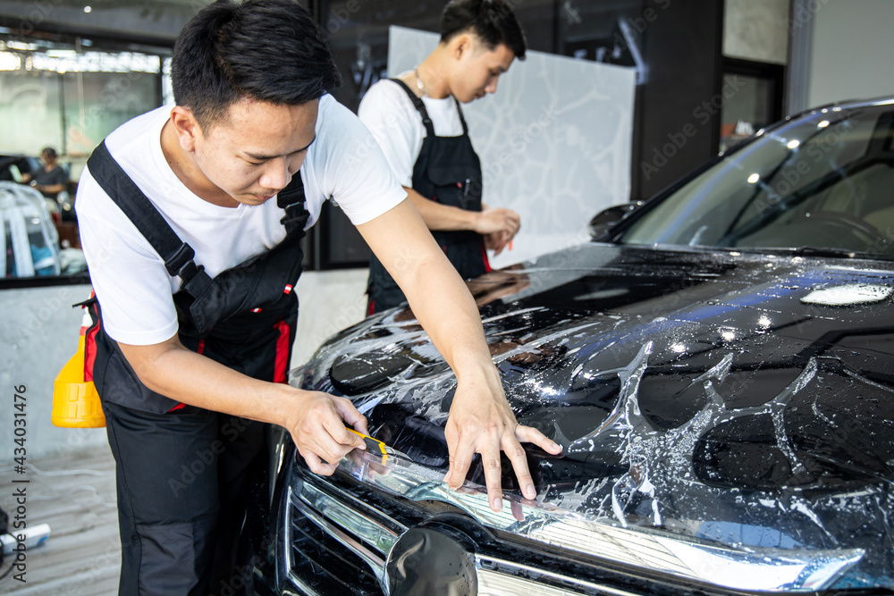 Mechanic installs car paint protection film. Mechanic installs car paint protection film.