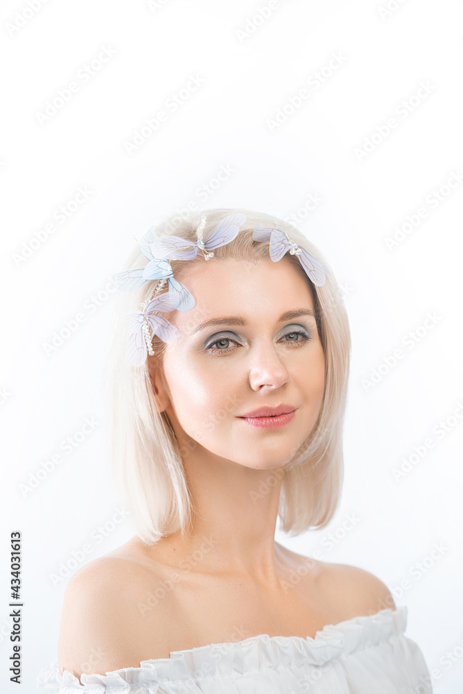 delicate portrait of a beautiful young blonde woman with a decoration in her hair on a white background. She smiles gently, her skin glowing delicate portrait of a beautiful young blonde woman with a decoration in her hair on a white background. She smiles gently, her skin glowing