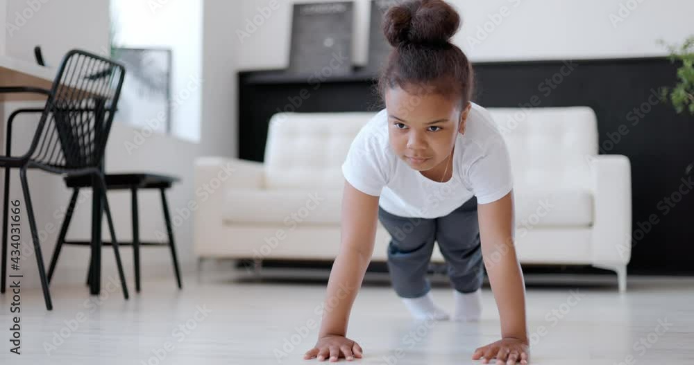 Happy african american girl exercising at home, push-ups. Happy african american girl exercising at home, push-ups.