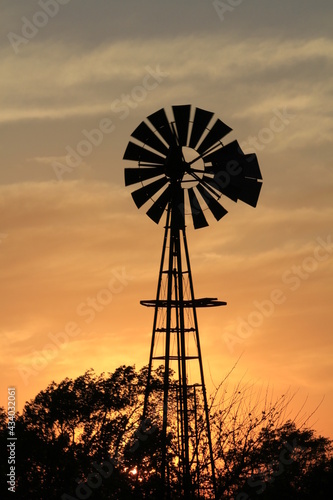 windmill at sunset on a farm with clouds and a colorful sky north of Hutchinson Kansas USA.