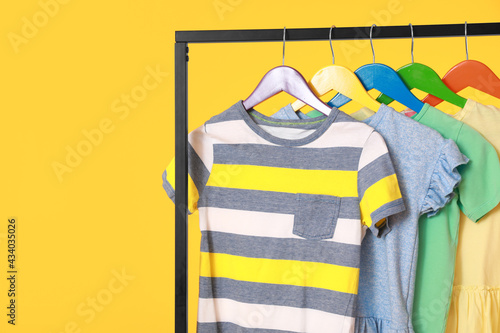 Rack with stylish clothes on color background, closeup