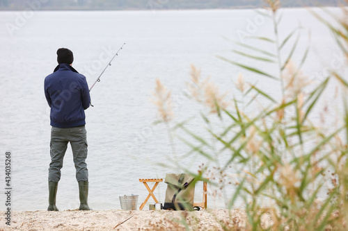 Man fishing on lake shore, ...
